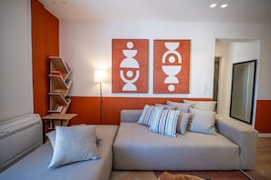 A modern living room with a sofa, pillows, a bookshelf, and abstract wall art. - LIV - Upscale Athenian Apartment 3B (Athens)