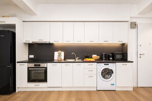 Eine moderne Küche mit weißen Schränken, einem Kühlschrank von Bosch, einem Backofen von Bosch, einer Waschmaschine und einer Mikrowelle.