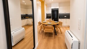 Una cucina moderna con mobili bianchi, un frigorifero nero e un tavolo da pranzo per quattro persone.
