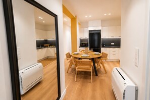 Eine moderne Küche mit weißen Schränken, einem schwarzen Kühlschrank und einem Esstisch für vier Personen.