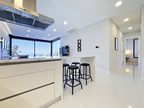A modern kitchen with a large island, bar stools, and a view of the sea. - Pearl of Madeira by Atlantic Holiday (Calheta)
