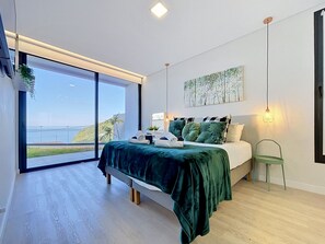 A modern bedroom with a large bed, a view of the outdoors, and a minimalist design. - Pearl of Madeira by Atlantic Holiday (Calheta)