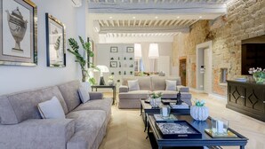 A modern living room with a sofa, coffee table, and decorative items. - The Gilded Residence (Lucca)