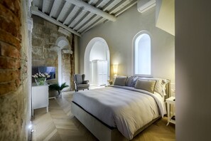 Ein Schlafzimmer mit einem großen Bett, einem Fernseher, einem Sessel und einem Schreibtisch.