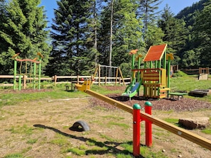 Un parque infantil con un balancín, estructuras para escalar y un tobogán.
