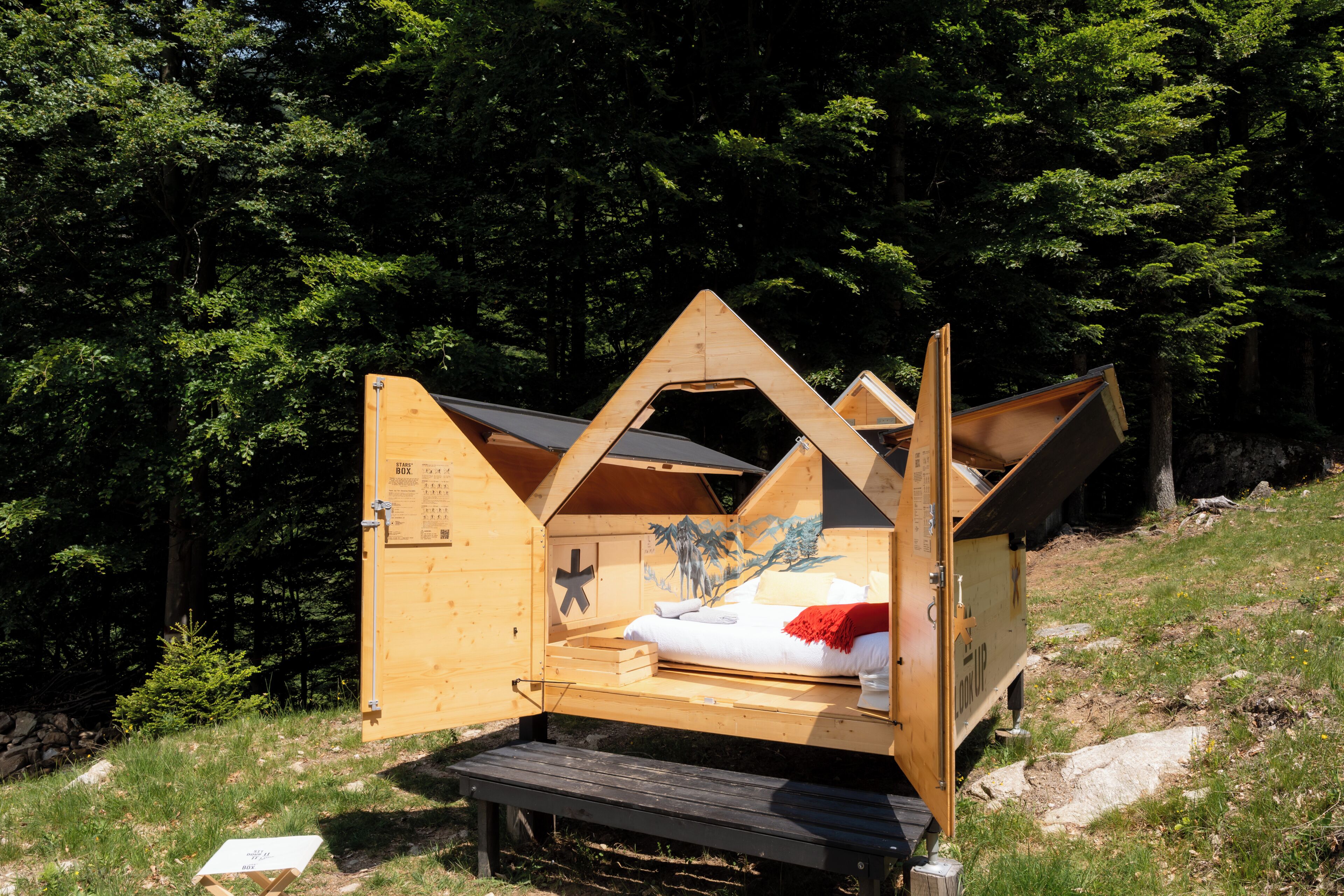 Eine Holzhütte mit einem Bett, einem kleinen Tisch und einer Bank.