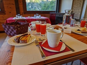A breakfast setting with a table, plates of food, a coffee pot, and a window view.