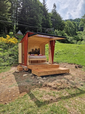 A small wooden cabin with a loft bed, a small table, and a bench. - Glamping Alpe Campo Rimasco (Rimasco)