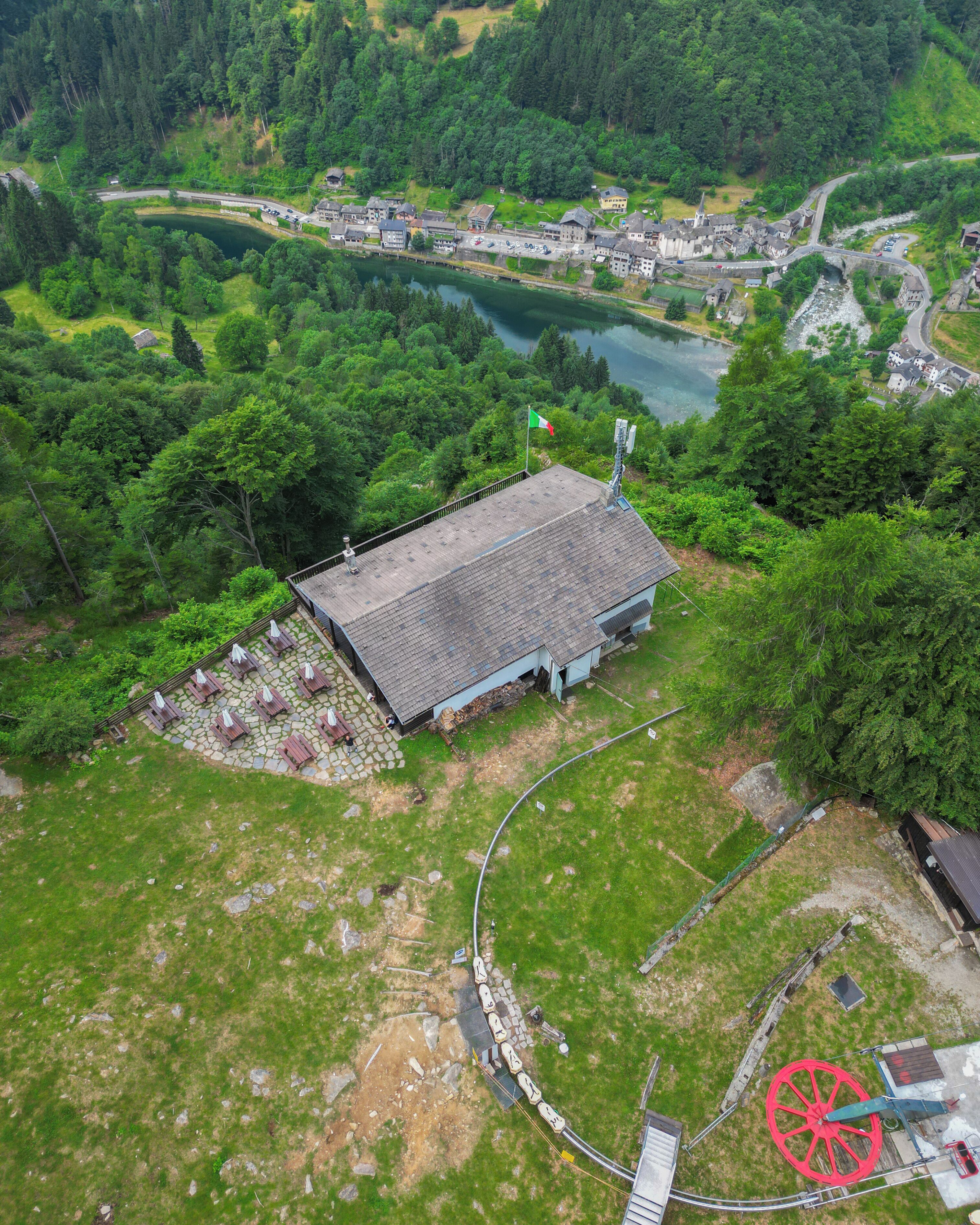 An aerial view of a building surrounded by greenery, a lake, and a small bridge.