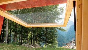 A room with a large skylight, a view of a forest, and a mountainous landscape. - Glamping Alpe Campo Rimasco (Rimasco)