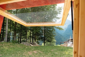 A room with a large skylight, a view of a forest, and a mountainous landscape. - Glamping Alpe Campo Rimasco (Rimasco)