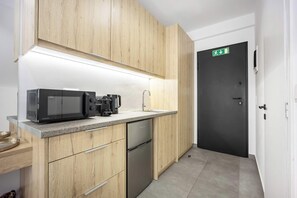 Eine moderne Küche mit Holzausstattung, einer Mikrowelle, einer Kaffeemaschine und einem Geschirrspüler.