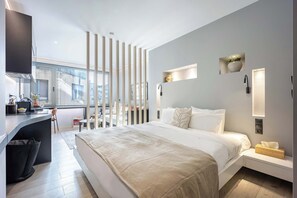 Una habitación de hotel moderna con cama, mesita de noche y un espacio de escritorio.