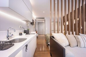 Ein modernes Hotelzimmer mit Küchenzeile, einem Bett mit vielen Kissen und einer Holzwand.