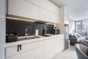 A modern kitchen with integrated appliances, a large window, and a seating area with a sofa and chairs. - Spacious 2BR in Psirri  2Baths  & Acropolis View (Athens)