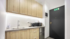 Une cuisine moderne avec des meubles en bois, un évier en acier inoxydable, une machine à café, une bouilloire, un four à micro-ondes et un réfrigérateur noir.