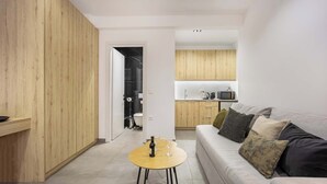 Un salon moderne avec un mur d’accent en bois, une table basse ronde, un canapé avec des coussins et une cuisine en arrière-plan.