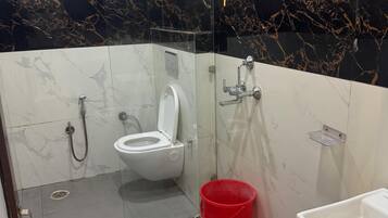 A bathroom with a toilet, shower, and sink.