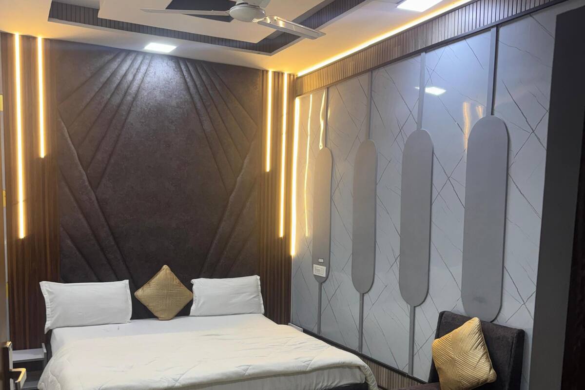 A modern bedroom with a large bed, a ceiling fan, and wall-mounted lighting.