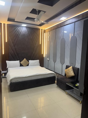 A modern bedroom with a large bed, a ceiling fan, and wall-mounted lighting.