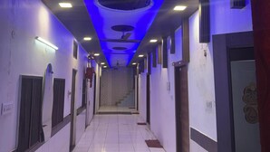 A corridor with a tiled floor, recessed lighting, and a staircase at the end. - Hotel American (Saharanpur)