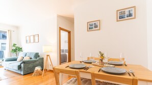 A dining area with a wooden table set for two, a sofa, and a lamp.