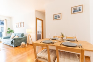 Ein Essbereich mit Holztisch, gedeckt für zwei Personen, einer Couch und einer Lampe.