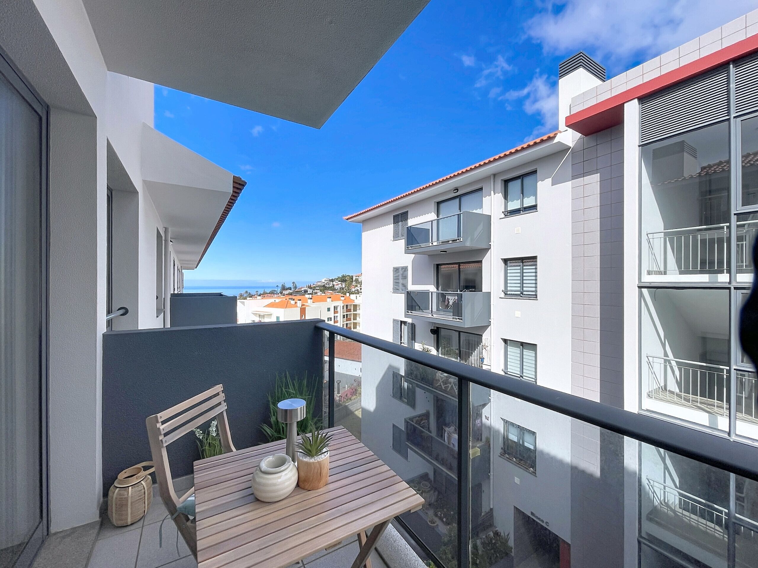A balcony with a table, chair, and potted plants.
