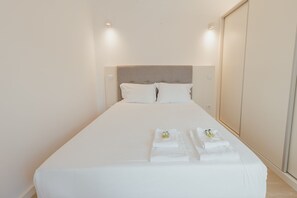A hotel room with a large bed, two pillows, a headboard, and neatly folded towels on the bed. - Downtown Elegant Studio by Vacationy (Porto)
