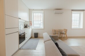 A modern kitchen with built-in appliances, a dining area with a table and chairs, and a sofa. - Downtown Elegant Studio by Vacationy (Porto)