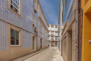 Eine schmale Straße, gesäumt von Gebäuden mit Kachelfassaden, unter einem wolkenlosen Himmel.