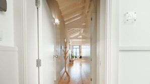 Een hal met houten vloer, witte muren en een plafond met zichtbare balken.