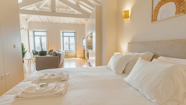 Een hotelkamer met een groot bed, een zithoek en uitzicht op de stad.