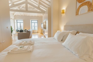 A hotel room with a large bed, a dining area, and a view of the city. - Boavista Charming by Vacationy (Porto)