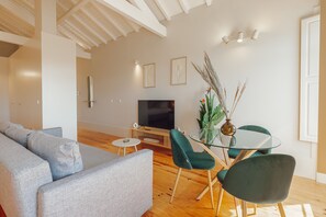 A modern living room with a sofa, a glass dining table, and chairs. - Boavista Charming by Vacationy (Porto)