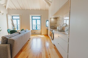 A modern kitchen with wooden flooring, a built-in washing machine, and a large window. - Boavista Charming by Vacationy (Porto)