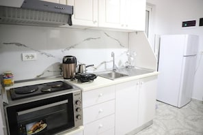 A kitchen with a built-in oven, a stovetop, a sink, and a white refrigerator.