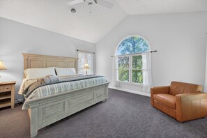 A bedroom with a bed, a window with a view, a chair, and a nightstand. - Lakefront retreat with private dock, lake views, spacious decks, pool table, and sun room! (Pulaski)