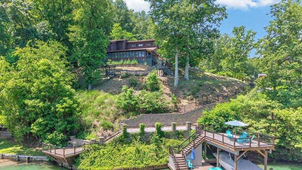 A lakeside property with a wooden dock, a small boat, and a house with a deck. - Lakefront retreat with private dock, lake views, spacious decks, pool table, and sun room! (Pulaski)