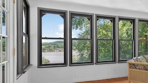 A room with large windows, wooden flooring, and a wicker chair. - Lakefront retreat with private dock, lake views, spacious decks, pool table, and sun room! (Pulaski)