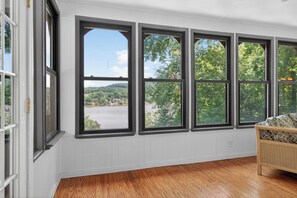 A room with large windows, wooden flooring, and a wicker chair.