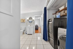 A compact bathroom with a toilet, sink, mirror, and a washing machine. - Lakefront retreat with private dock, lake views, spacious decks, pool table, and sun room! (Pulaski)