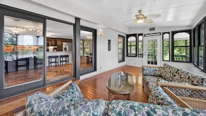 A spacious living area with large windows, a ceiling fan, and a view of the kitchen. - Lakefront retreat with private dock, lake views, spacious decks, pool table, and sun room! (Pulaski)