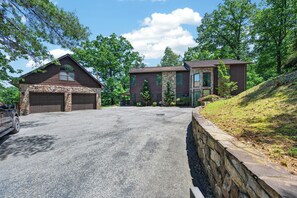 A two-story house with a stone facade, a garage, and a driveway. - Lakefront retreat with private dock, lake views, spacious decks, pool table, and sun room! (Pulaski)