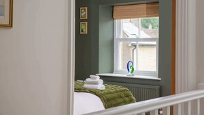 Una camera da letto con una finestra, un termosifone e un letto con coperta verde.