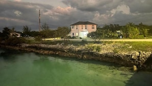 Una casa de dos pisos con puerta principal, un porche pequeño y una vista despejada del agua al frente.