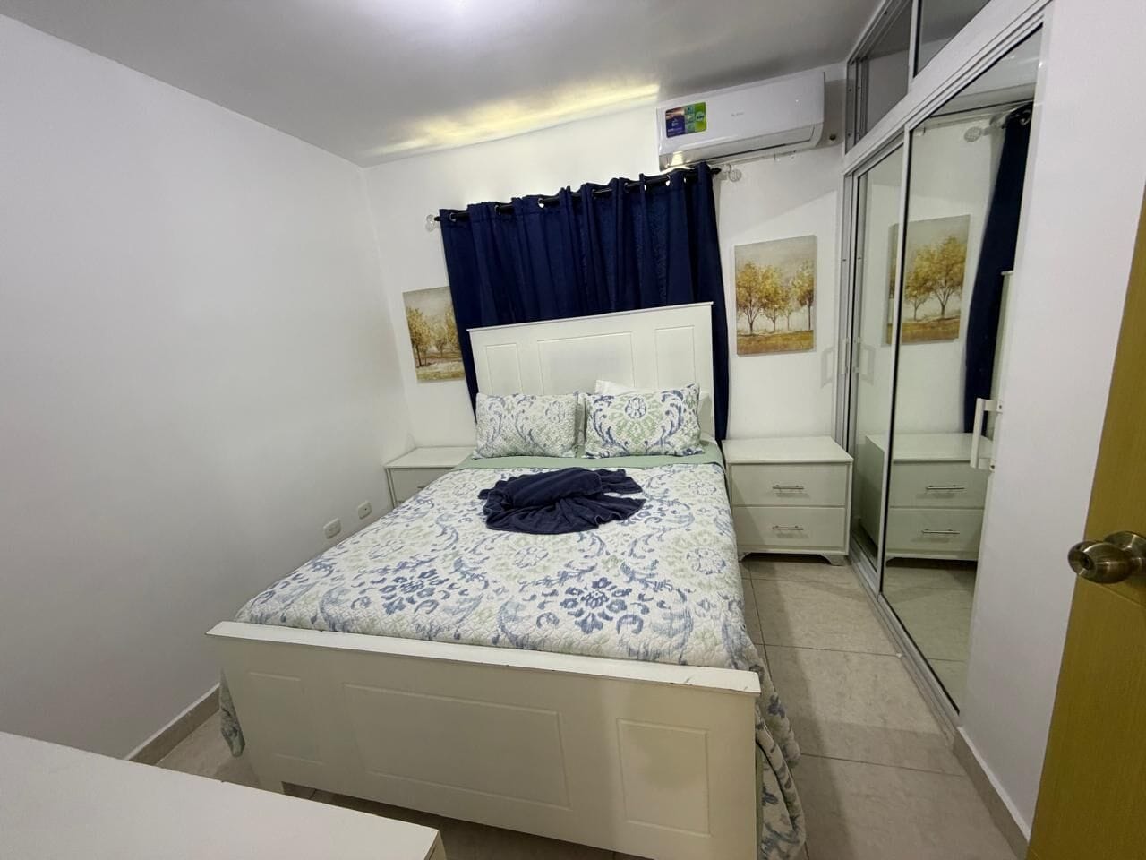 A bedroom with a bed, bedside tables, a wardrobe, and a mirror.