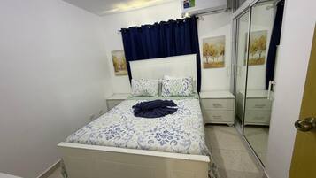 A bedroom with a bed, bedside tables, a wardrobe, and a mirror.