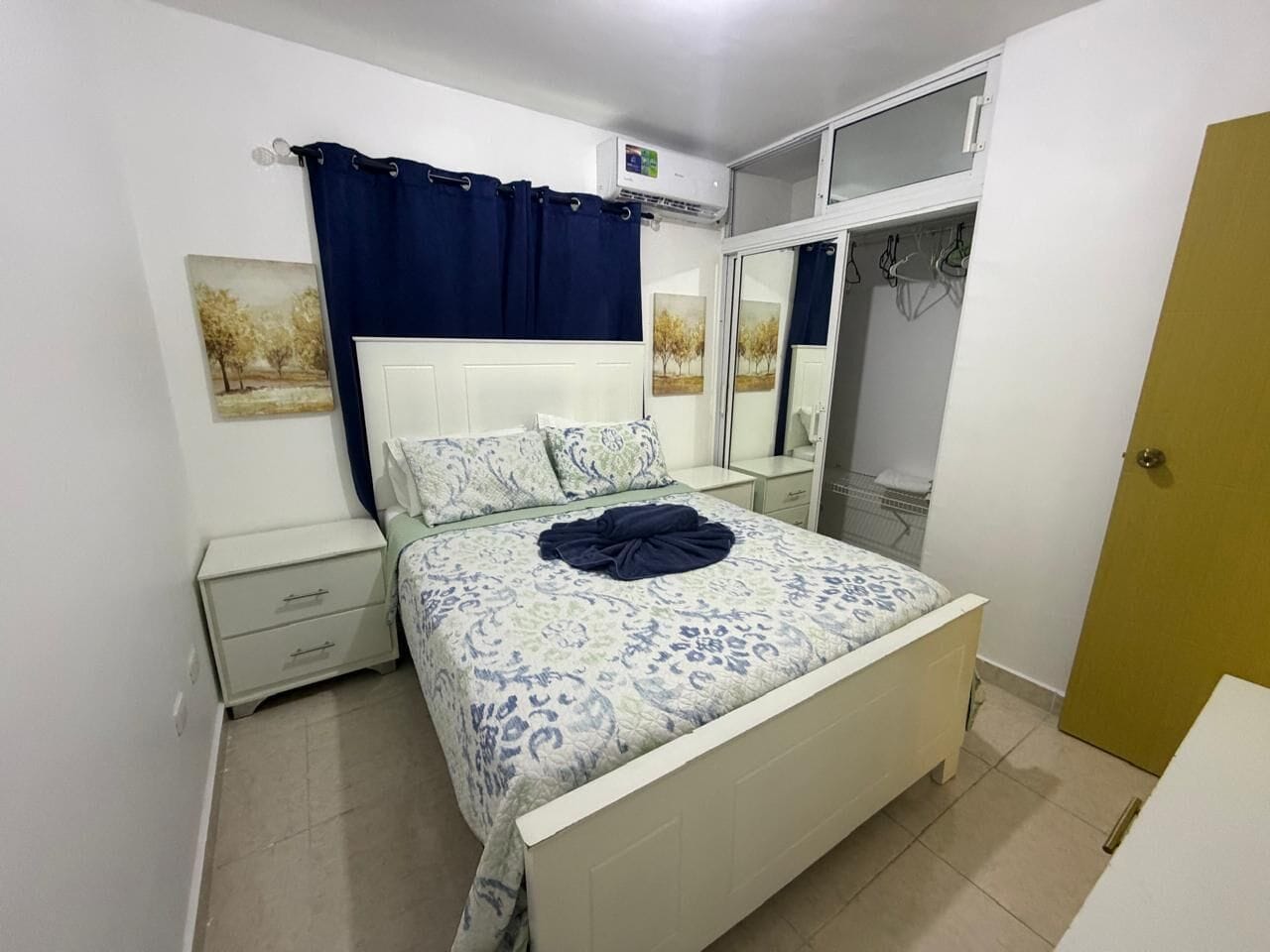 Un dormitorio con cama, mesita de noche, cómoda, armario y espejo.