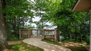 A wooden deck leading to a lake, surrounded by trees and a concrete path. - Lakeside retreat minutes walk from Douglas Beach! (Douglas)